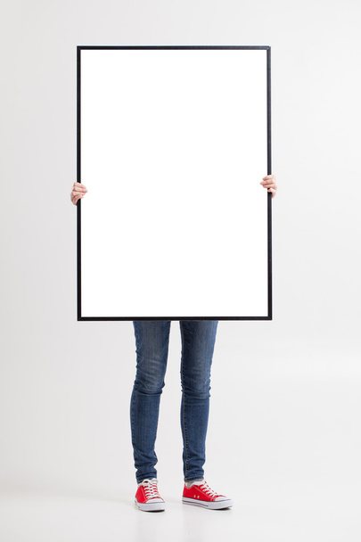 woman with blank poster on wall background - Φωτογραφία, εικόνα