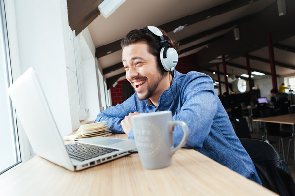Cheerful man in headset using laptop - Zdjęcie, obraz