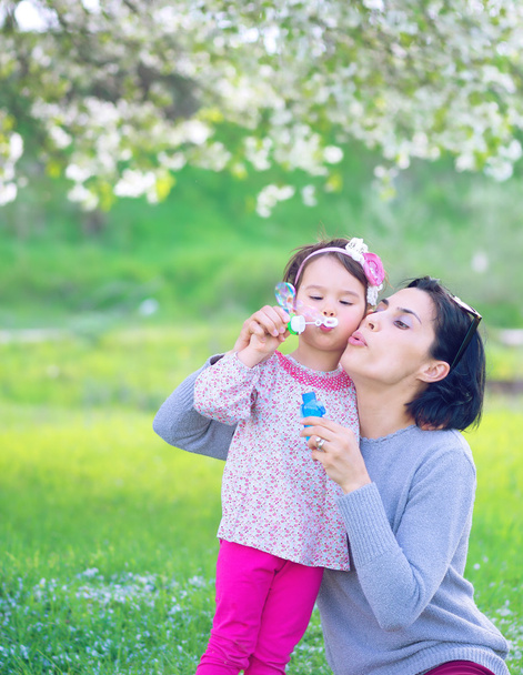 Boldog fiatal anya és lánya szappanbuborék fújás Park - Fotó, kép