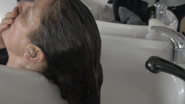Stylist hairdresser washing hair in basin - Footage, Video