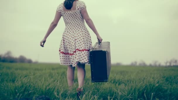 γυναίκα ντυμένη σε στυλ ρετρό φέρνει αποσκευών μέσα από το πράσινο πεδίο αργή κίνηση - Πλάνα, βίντεο