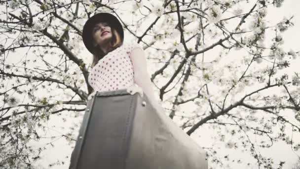 młoda kobieta ubrana w stylu retro pozowanie w kwitnący ogród zwolnionym tempie - Materiał filmowy, wideo