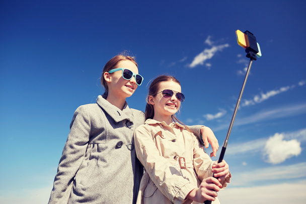 happy girls with smartphone selfie stick - Foto, imagen