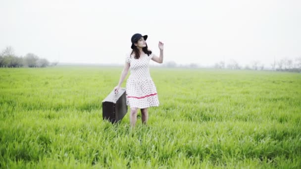 женщина одета в ретро стиль несет багаж через зеленое поле замедленной съемки
 - Кадры, видео