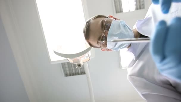 Der Zahnarzt überprüft den Mund mit Werkzeugen. Sicht des Patienten im Stuhl. - Filmmaterial, Video