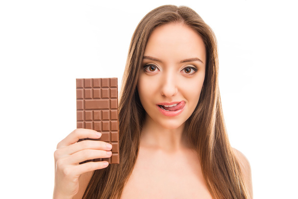 Pretty girl holding bar of chocolate and licking her lips - Фото, зображення