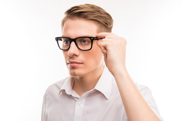 Attractive young man in white shirt touching his glasses - Foto, Bild