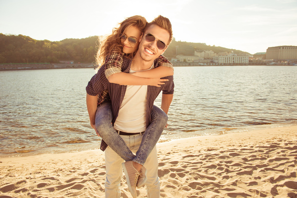 Happy young man piggybacking his pretty woman at the seaside - Photo, Image