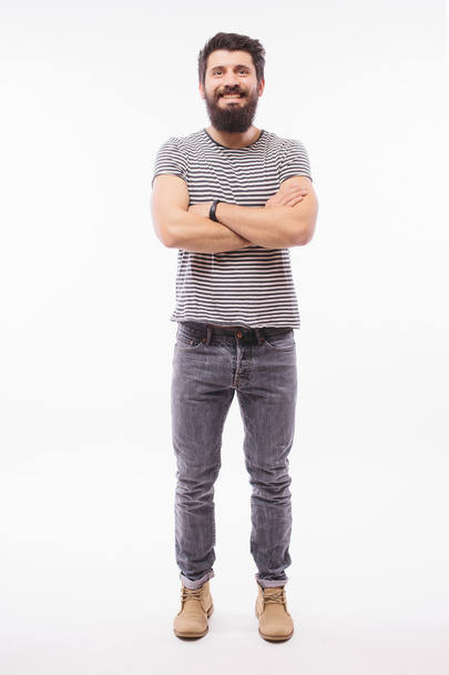 Komea nuori mies, jolla on parta täynnä korkeutta ristissä kädet seisoessaan valkoista taustaa vasten
 - Valokuva, kuva