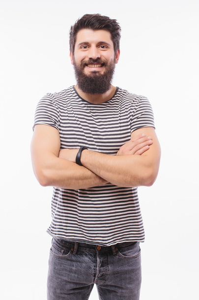 Portrait handsome young man with beard with crossed hands smiling while standing against white background - Φωτογραφία, εικόνα