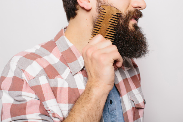 Side portrait of handsome caucasian man with funny mustache smile and comb his big against white background. - 写真・画像
