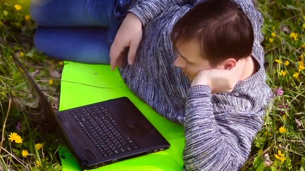 Az ember egy laptop a parkban fekvő pihenő - Felvétel, videó