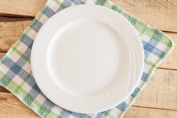 Clean plate with napkin on wooden background. - Photo, Image