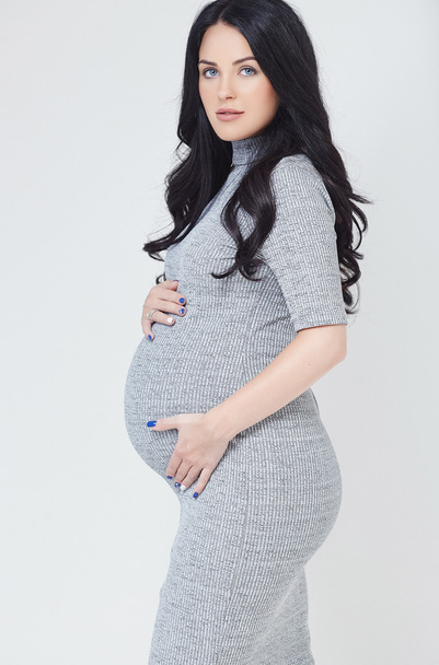 Pregnant brunette woman in a grey dress - Foto, immagini