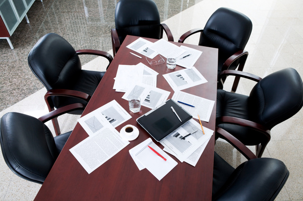 Leerer Sitzungssaal: schwarze Stühle am Tisch mit Geschäftsobjekten darauf - Foto, Bild