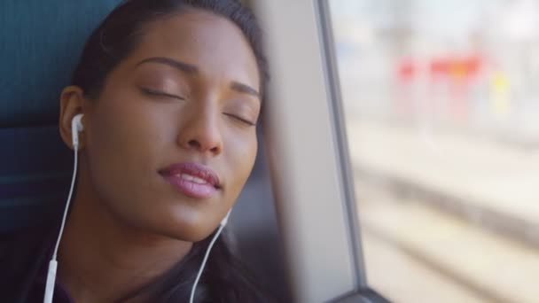  woman with earphones relaxing on train journey - Filmati, video