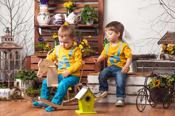 Children on the background of spring decor in yellow T-shirts , flower meadow . - Foto, Imagen