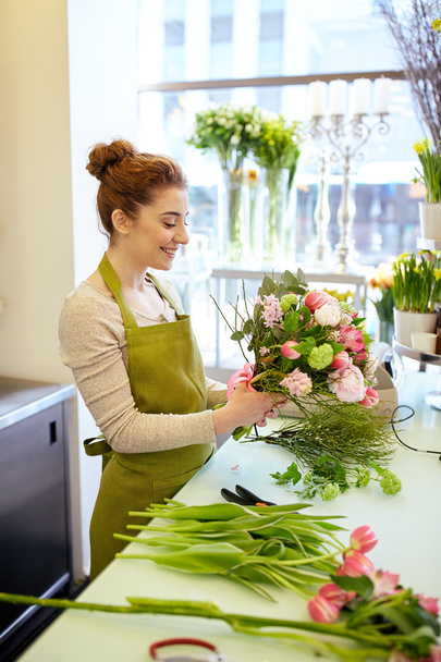 smiling florist woman making bunch at flower shop - Fotó, kép