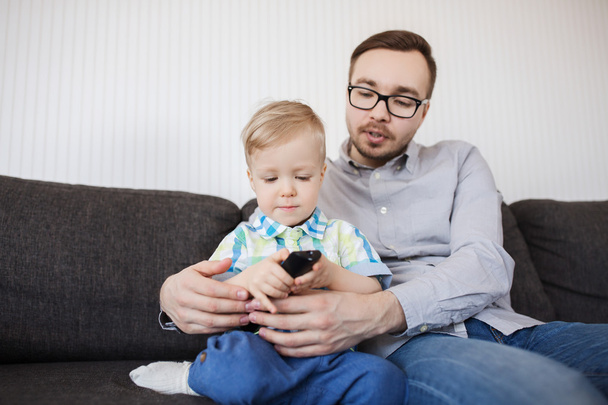 father and son with remote watching tv at home - Foto, Bild