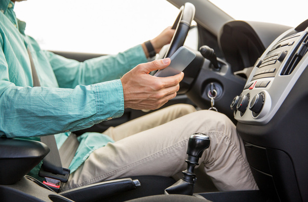 close up of man with smartphone driving car - Foto, Bild