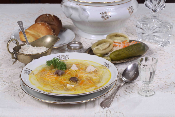 Rosół z makaronem w naczyniu i marynowane warzywa - Zdjęcie, obraz