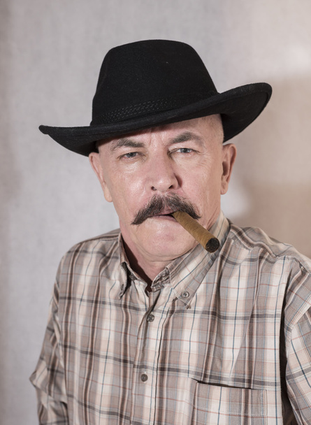The cowboy with mustache, in a black hat smoking a cigar - Fotoğraf, Görsel