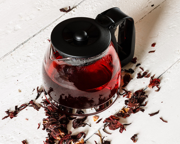 Kettle of Karkadeh Red Tea on wooden table - Fotó, kép