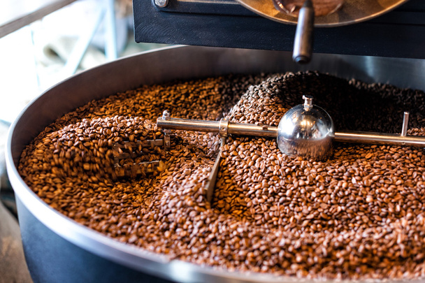 Freshly roasted coffee beans from a large roaster in the cooling cylinder. Motion blur on beans. - Fotografie, Obrázek