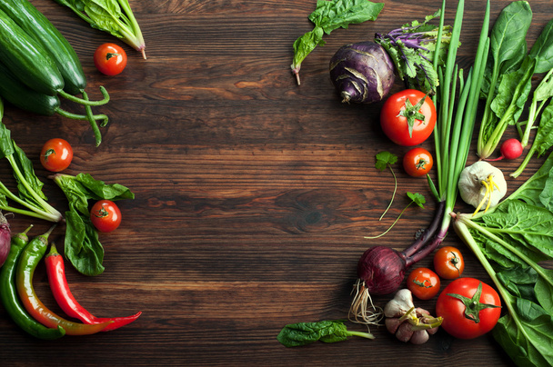 Fresh juicy vegetables and herbs, such as radishes, onion, spinach, tomatoes and hot peppers on a brown wooden board. Vegan concept. Vegetable background. Space for text - Foto, Imagen