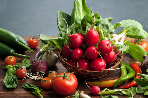 Fresh juicy vegetables and herbs, such as radishes, spinach, tomatoes and hot peppers on a brown wooden board. Vegan concept. Vegetable background. Space for text - Foto, Bild