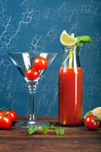 Tomato juice in a glass and bottle on a wooden board. Blue background. Vegetarian concept. Non-alcoholic cocktail of tomato juice - Foto, Imagen
