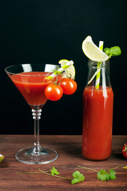 Tomato juice in a glass and bottle on a wooden board. Black background. Vegetarian concept. Non-alcoholic cocktail of tomato juice - Φωτογραφία, εικόνα