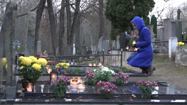 jovem mulher ajoelhar-se no túmulo mãe avó colocar vela e rezar. 4K
 - Filmagem, Vídeo