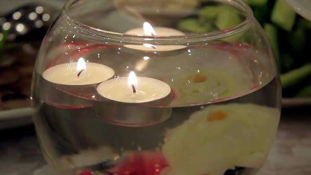 Brandende kaarsen drijvend in een decoratieve vaas - Video