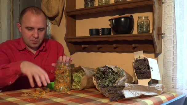 Male gardener put dried marigold calendula blooms herbs in glass jar. 4K - Footage, Video