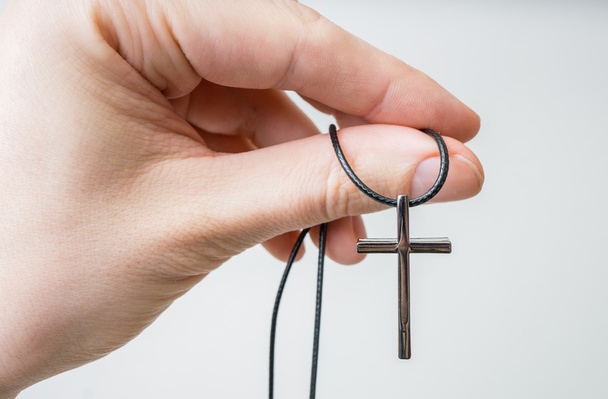 Man holds nwecklace with cross in hand. - Foto, afbeelding