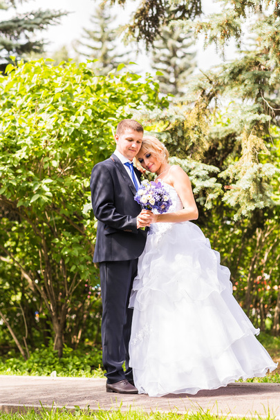 Onu açık havada kucaklayan Düğün çifti, sarılma bir buket çiçek, holding gelin damat - Fotoğraf, Görsel