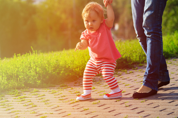 first steps of little girl in summer park - Photo, Image
