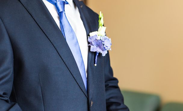Прекрасный свадебный бутоньер на костюме жениха крупным планом
 - Фото, изображение