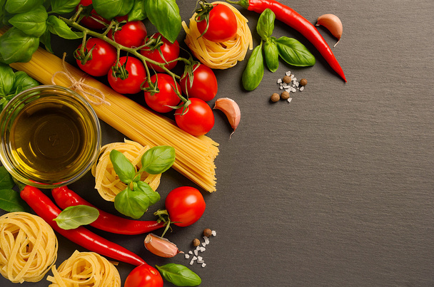 Pasta, groenten, kruiden en specerijen voor Italiaanse gerechten op zwarte achtergrond - Foto, afbeelding
