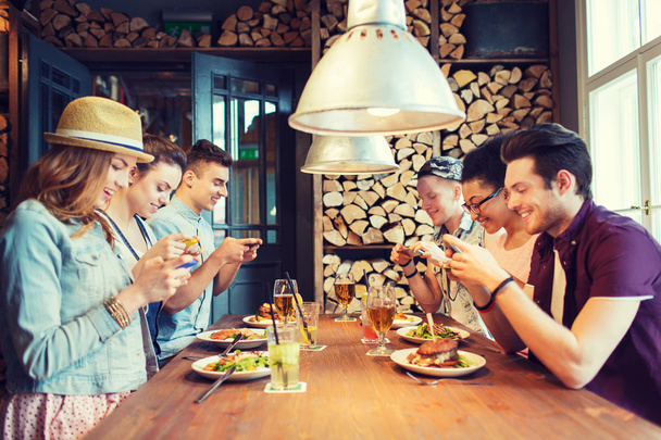 счастливые друзья со смартфонами, представляющие еду
 - Фото, изображение