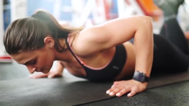 Athletic young woman doing push-ups. Close-up front view of smart watch - Footage, Video