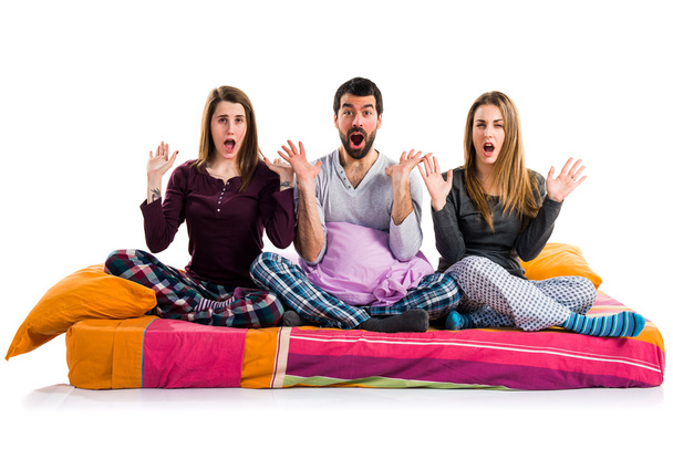 Three friends on a bed doing surprise gesture - Foto, imagen
