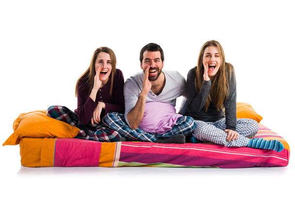Three friends on a bed shouting - Foto, afbeelding