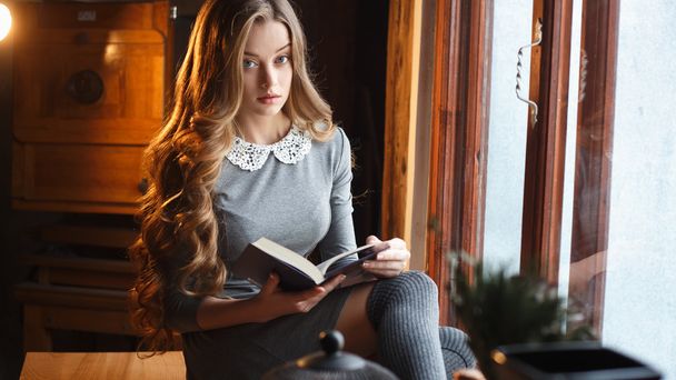 Elegant young lady with a classic book in expensive interior - Zdjęcie, obraz