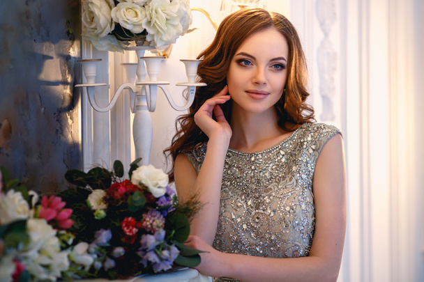 Beautiful young lady in a luxury dress in elegant interior with a bouquet of flowers - Foto, Imagem
