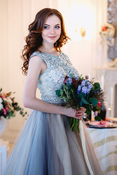 Beautiful young lady in a luxury dress in elegant interior with a bouquet of flowers - Foto, immagini