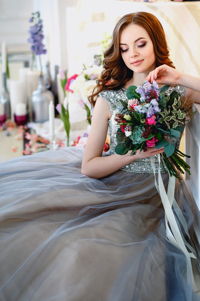 Beautiful young lady in a luxury dress in elegant interior with a bouquet of flowers - Foto, Imagem
