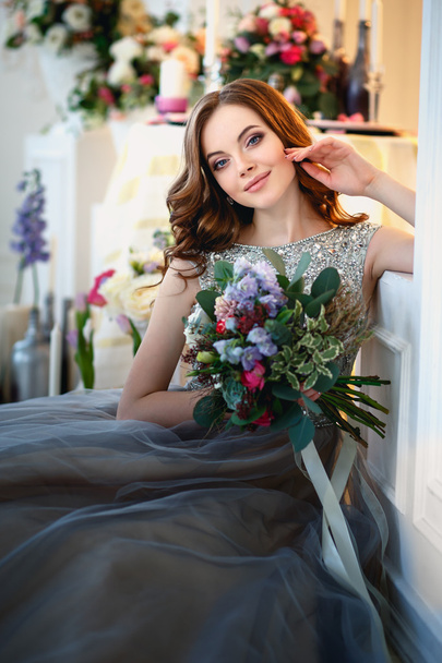 Beautiful young lady in a luxury dress in elegant interior with a bouquet of flowers - Valokuva, kuva