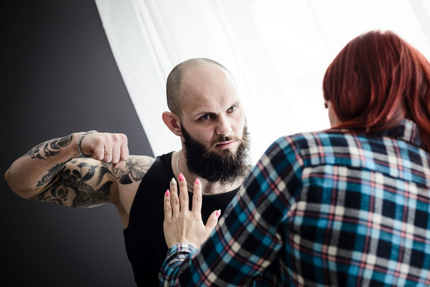 Τατουάζ μυώδης άνδρας ξυλοδαρμό της συζύγου του redheaded. - Φωτογραφία, εικόνα